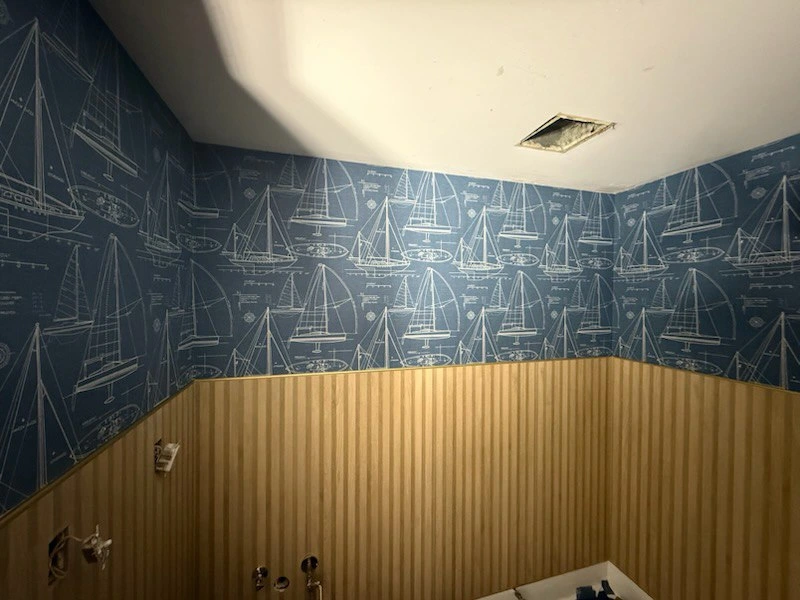 Professional wallpaper installer applying wall covering with precision tools